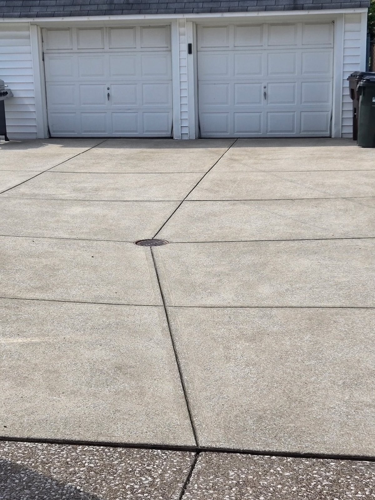 The same residential concrete driveway after cleaning with a visibly brighter surface