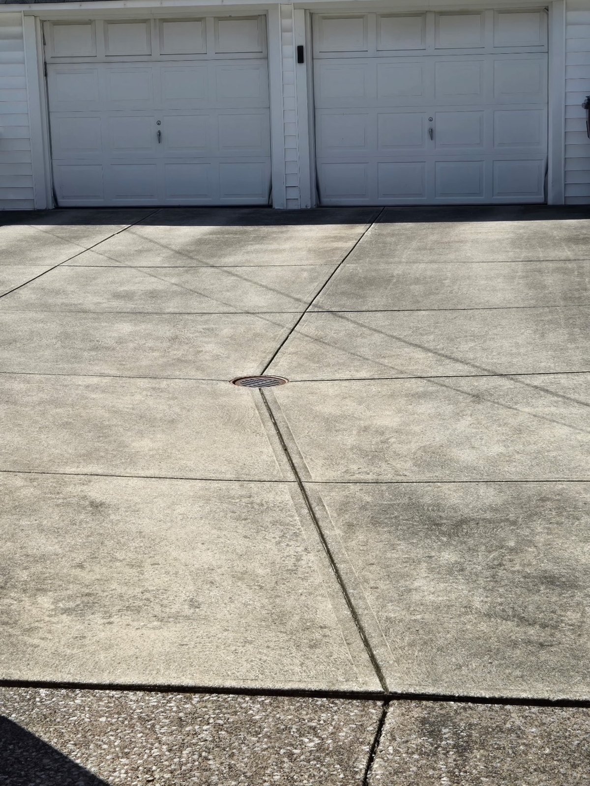 Residential concrete driveway with dark organic buildup before cleaning